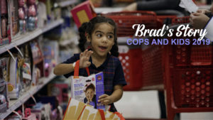 Young girl adding a toy to her bag at KC FOP KCPD Cops and Kids event. Reads "Brad's Story: Cops and Kids 2019"
