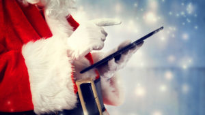 Santa Claus using a tablet on snowy night