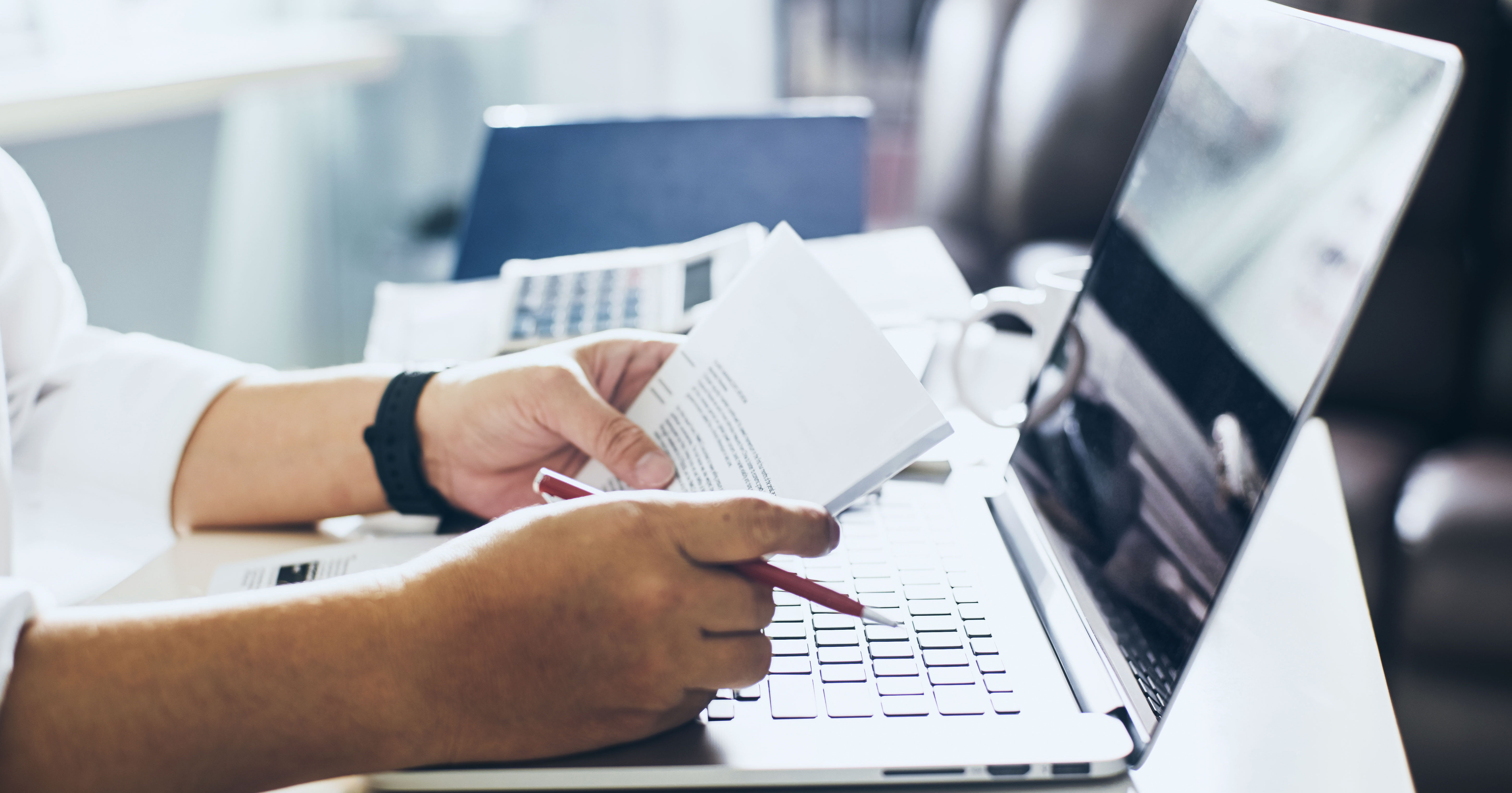Man working at laptop holding stack of bills