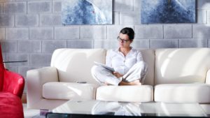 Woman sitting in decorated apartment working on iPad tablet