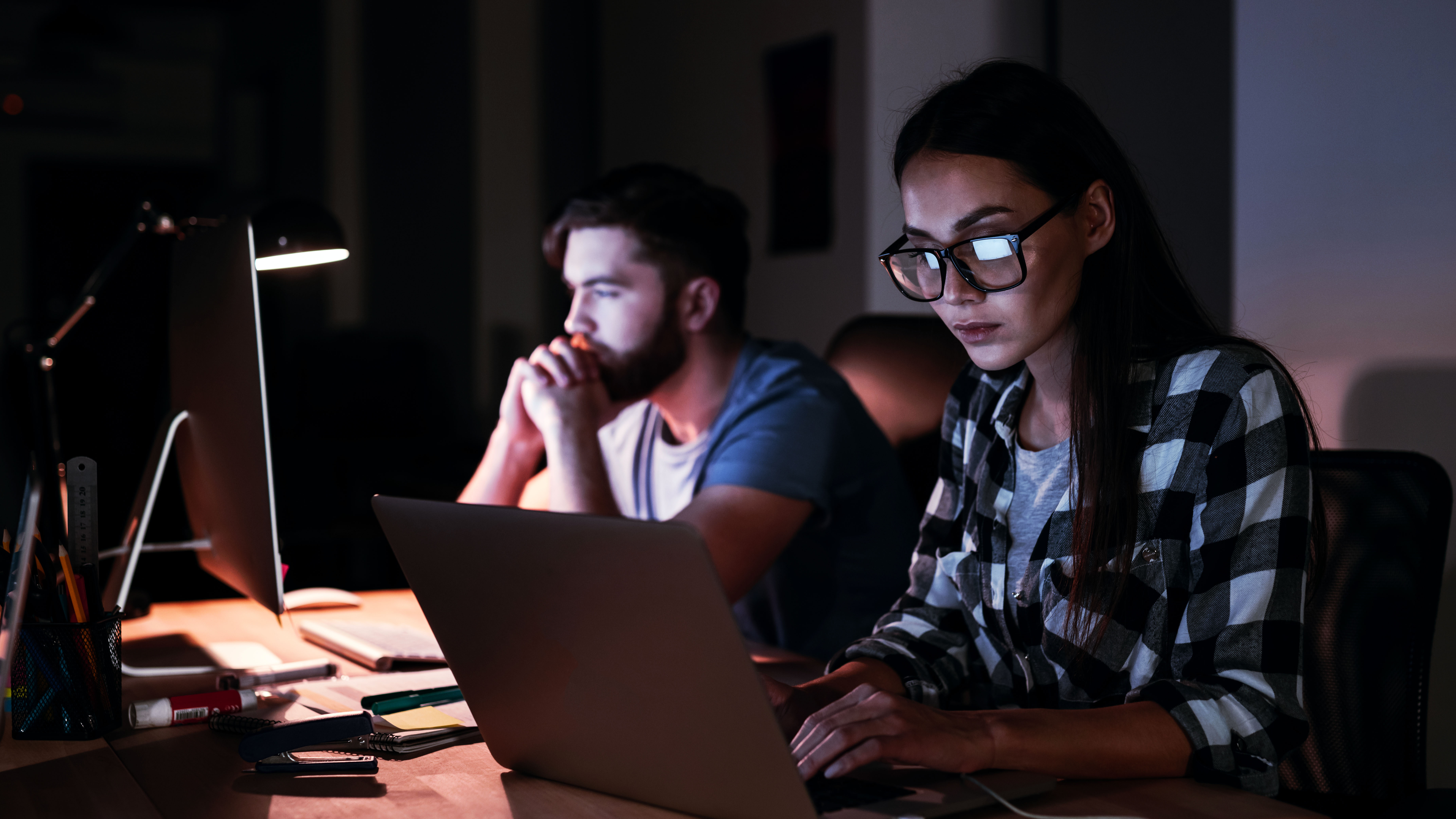 Man and woman using a desktop and laptop computer. Reads "Emergency Financial Assistance"