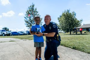 Police Officer and young boy smiling and posing together with a fishing pole. Taken at Olathe Police Department Fishing with the Cops event